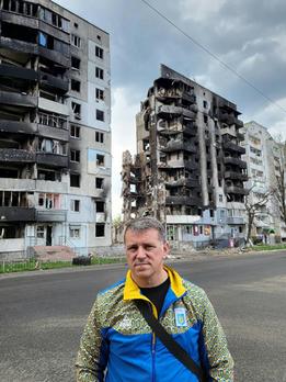 Image of Mikhail Geraskevych on a street of gutted homes in Kyiv.