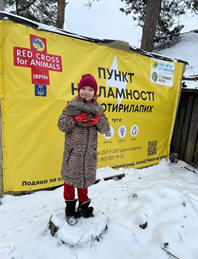 Image of a young Ukrainian picking up dog food at the Red Cross for Animals center